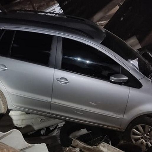 Carro vai parar dentro de oficina mecânica pelo telhado 