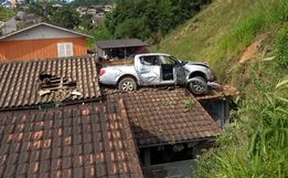 Camionete para em cima de residência após acidente